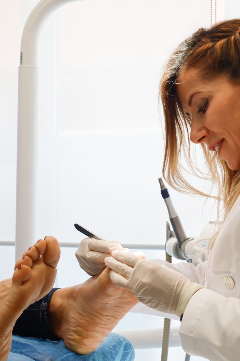 Podóloga realizando tratamiento podológico a un paciente en consulta con instrumental especializado