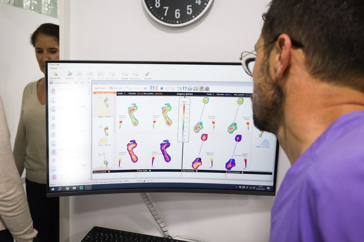 Podólogo en clínica de Alicante analizando un estudio de la pisada digital en pantalla, valoración biomecánica.